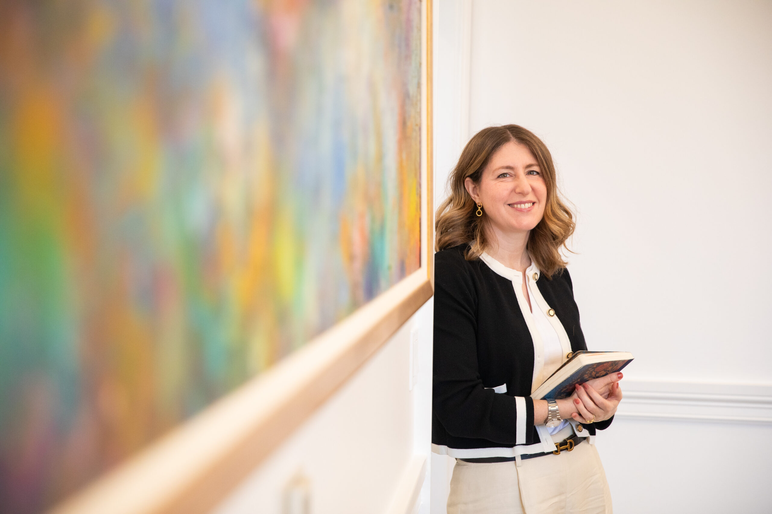 Amy Rogan-Mehta, executive vice president and chief of staff, stands next to a painting in her office in Memorial Hall.